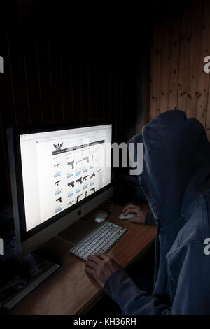 Image Concept de cyber à capuchon, l'homme criminel à l'aide d'ordinateur pour accéder à la page internet web profond offrant des armes à feu, Banque D'Images