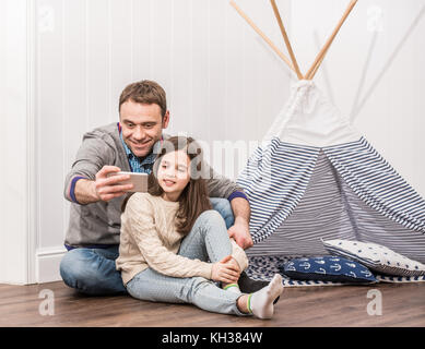 Père et fille se jouant à la maison selfies construit avec wigwam Banque D'Images