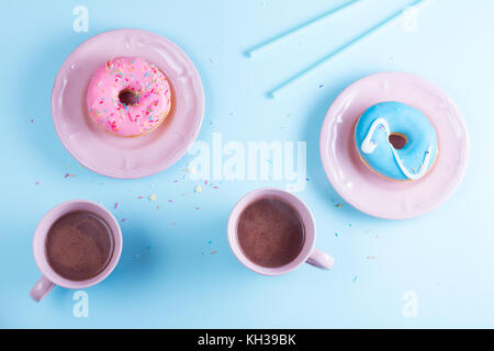Deux des beignets sucrés avec deux tasses de cacao sur fond rose et bleu avec copie espace, scène Vue de dessus Banque D'Images