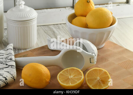 Citrons frais bio-blanc et jaune avec les agrumes centrifugeuse à main, léger et lumineux sur une planche à découper en bois Banque D'Images