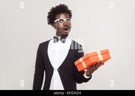 Étonnement man holding gift box et choqué. studio shot, fond gris Banque D'Images