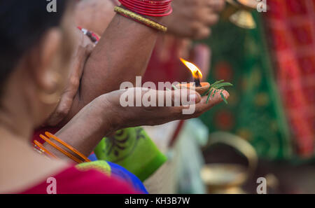 Femme hindoue indienne main tenant une lampe d'argile à la main et une plante sacrée pour offrir dans le Gange comme partie d'un rituel à Varanasi en Inde. Banque D'Images