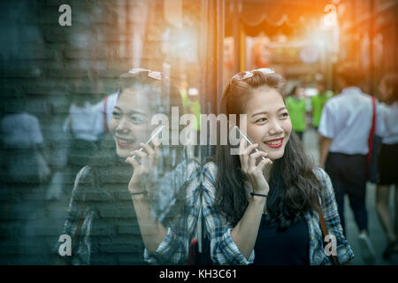 Portrait de jeune femme asiatique parlant à pleines dents téléphone intelligent visage souriant avec bonheur l'émotion Banque D'Images