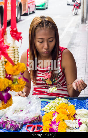 Jeune fille faire des guirlandes de fleurs sur une rue de Bangkok, Thaïlande Banque D'Images