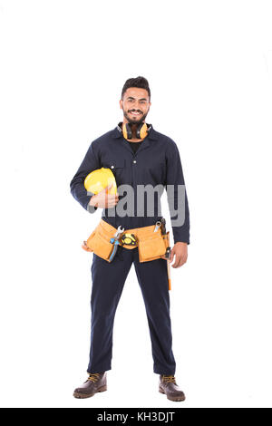 Toute la longueur de balle happy worker smiling barbe et tenant un casque jaune, bleu foncé mec Vêtements et équipement de la courroie, isolated on white backg Banque D'Images