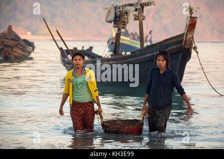 Les jeunes fishwives rapprocher les nuits à terre des prises à l'aube sur la plage de Ngapali dans l'État de Rakhine au Myanmar (Birmanie). Banque D'Images