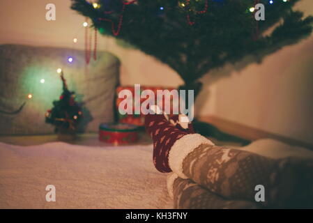 Jambes femme chaude en bas de Noël reposant in front of Christmas Tree Banque D'Images