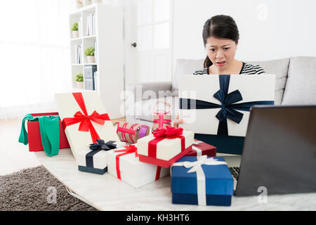 Jeune fille douce regardant don fort sentiment confus quand elle l'aide en ligne de l'ordinateur et a reçu de l'été saison vente présent à la maison. Banque D'Images