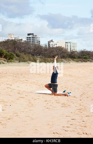 L'homme l'exécution de routines de yoga sur la plage à Alexandra Headland, Sunshine Coast, Queensland, Australie Banque D'Images