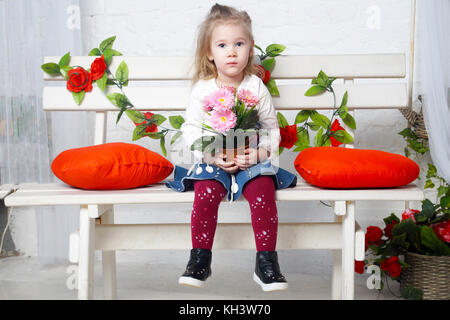 Peu de belle fille est assis sur le banc.portrait studio isolé Banque D'Images