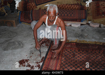 Un vieil homme démontrant comment il fait un tapis en Inde Banque D'Images