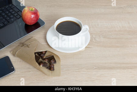 Vue de dessus du lieu de travail de travail,table en bois avec de l'espace vide, ordinateur portable, apple, tasse de café, chocolat noir à la noisette Banque D'Images