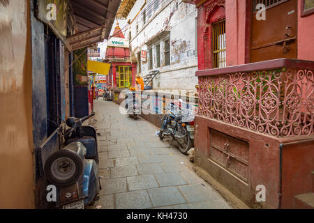 Ruelle étroite typique varanasi avec old weathered buildings anciens temples et deux roues en stationnement sur les deux côtés. Banque D'Images