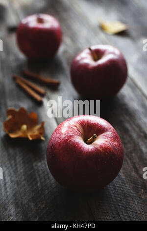 Des pommes rouges et des bâtons de cannelle sur fond de bois. La vie toujours des aliments de l'automne Banque D'Images