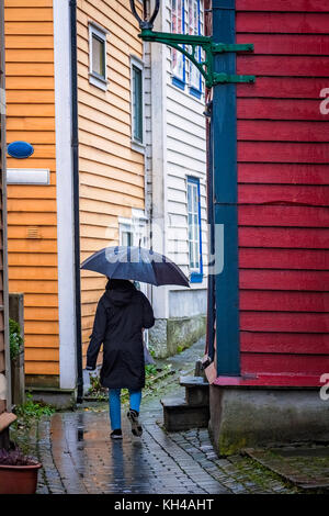 Personne non identifiée marchant avec un parapluie noir à travers les rues étroites en galets piqués entre les maisons traditionnelles colorées dans la vieille partie de Berg Banque D'Images