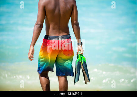 Les jeunes corps méconnaissables brésilien surfer marcher avec ses nageoires le long de la côte à l'arpoador beach, spot de surf populaire à Rio de Janeiro, Brésil Banque D'Images