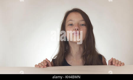 Belle adolescente coquine envoie joyeusement baisers à la air sur fond blanc Banque D'Images