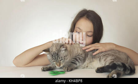 Belle cheerful girl avec un chat jouant avec green fidget spinner sur fond blanc Banque D'Images