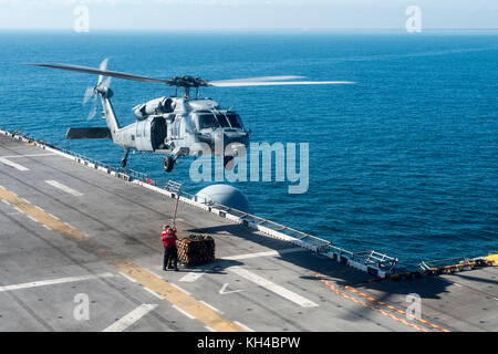 Les marins affectés au navire d'assaut amphibie USS Iwo Jima (DG 7) brancher une palette cargo sur la face inférieure d'un SH-60 Banque D'Images