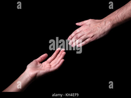 La main des hommes pour atteindre touch femme main. concept pour le salut de l'amitié de sauvetage aide orientation aider. fond noir. Dieu mains atteignant aidant Banque D'Images