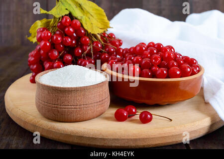 Viburnum rouge dans un bol en céramique, le sucre, un tas de petits fruits pour le thé, de la confiture. Banque D'Images