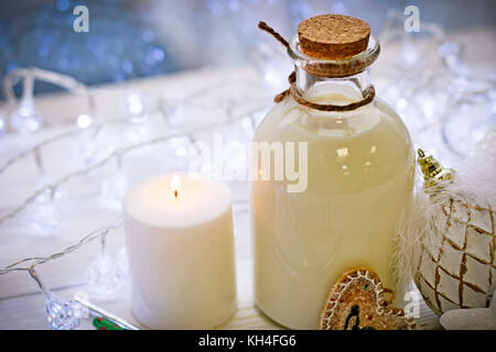 Une bouteille de lait, des boules et une bougie sur la table Banque D'Images