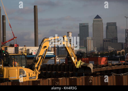Des travaux de construction sont en cours sur le Thames Tideway tunnel ou Super Sewer sur la Tamise près de Wapping, avec des excavateurs JCB travaillant en premier plan avec Canary Wharf et le quartier financier des Docklands comme arrière-plan à Londres, Angleterre, Royaume-Uni. Le Thames Tideway tunnel est un projet de génie civil en cours de construction tunnel de 25 km qui passe principalement sous la section des marées de la Tamise à travers le centre de Londres, qui permettra de capturer, de stocker et de transporter presque tous les rejets combinés d'eaux usées et d'eaux de pluie qui débordent actuellement dans la rivière. Banque D'Images