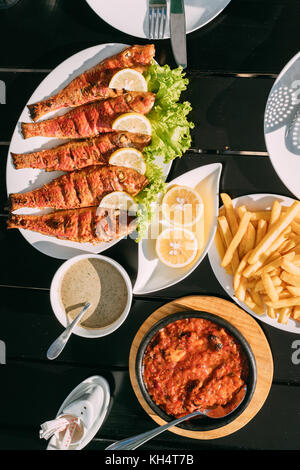 Batumi, Géorgie, l'Adjarie. plats de la cuisine nationale géorgienne : poêlée de rougets, poisson citrons, satsivi ou sauce de noix, compote et moules frites. Banque D'Images