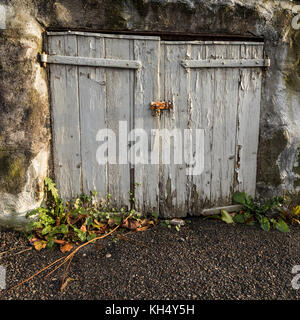 Vieilles portes grises peintes sur un hangar en pierre Banque D'Images