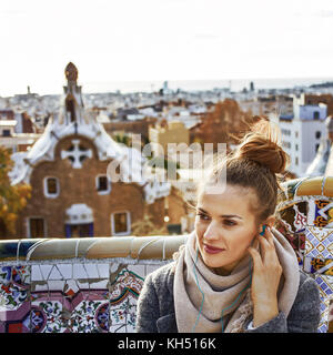 Style signature de Barcelone. Jeune femme manteau en tourisme à Barcelone, Espagne audioguide écoute alors que assis sur un banc Banque D'Images