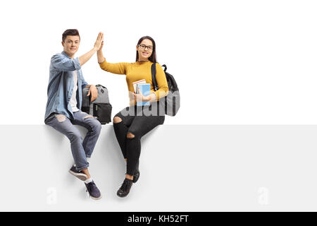 Étudiants adolescents assis sur un bord haut-fiving l'un l'autre et regardant la caméra isolé sur fond blanc Banque D'Images