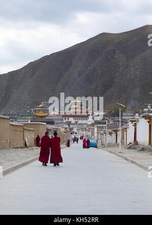 Moines tibétains marcher dans les rues de monastère de Labrang, province de Gansu, Chine, Labrang Banque D'Images