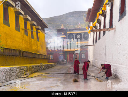 Les moines bouddhistes en robes rouges sont le nettoyage, monastère Rongwo Tongren County, Longwu, Chine Banque D'Images