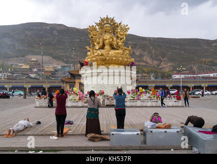 Les tibétains prier devant la statue de la déesse bouddhiste tara à l'extérieur du monastère longwu, comté de Tongren, Longwu, Chine Banque D'Images