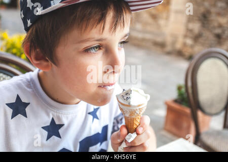 Jeune garçon mangeant une glace sur une terrasse en Italie Banque D'Images