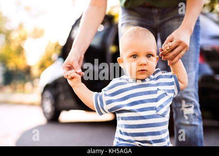 Jeune mère avec son petit garçon marcher par la voiture. Banque D'Images