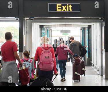 Les gens de quitter l'aéroport de Stansted via panneau de sortie de l'arrivée des vols internationaux Banque D'Images