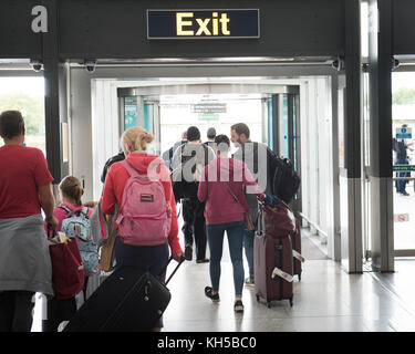 Les gens de quitter l'aéroport de Stansted via panneau de sortie de l'arrivée des vols internationaux Banque D'Images