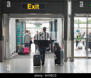 Les gens de quitter l'aéroport de Stansted via panneau de sortie de l'arrivée des vols internationaux Banque D'Images