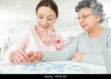 Petite-fille puzzle résoudre avec l'aide de sa grand-mère Banque D'Images
