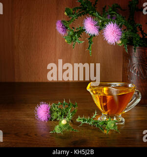 Plante à fleurs le chardon de lait et d'huile d'herbe de guérison. de verre sur fond de bois. l'espace libre pour le texte. Banque D'Images