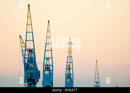 Conteneur bleu grues mobiles vu au coucher du soleil. Banque D'Images