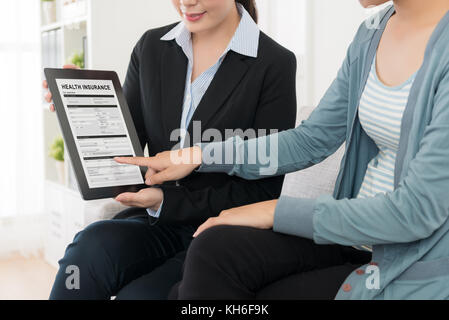 Belle femme élégante à souscrire à une assurance-maladie à la maison lors de l'agent professionnel manager visitant et utilisant l'ordinateur tablette mobile la signature. Banque D'Images