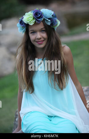 Une belle jeune fille de 12 ans habillé dans une robe bleu clair, portant une couronne de fleurs portefeuille bat mitzvah. Banque D'Images