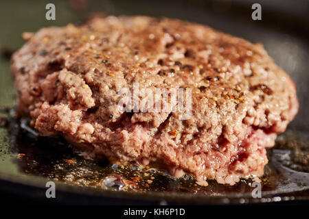 Un pâté d'hamburger sur un grill en fonte Banque D'Images