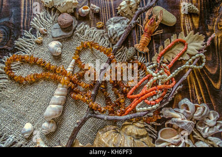 Perles de perles vieux rivière,corail rouge avec perles de couleur ambre à l'état brut sur toile avec des coquillages et des cailloux sur les conseils sombre Banque D'Images