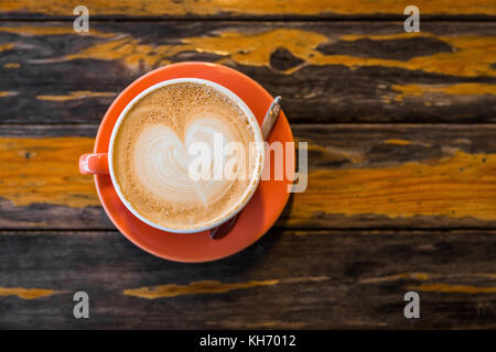 Fermer l'accent sur Vue de dessus d'orange tasse café latte chaud à côté de cuillerée à thé sur la table surface grunge avec l'espace. Banque D'Images