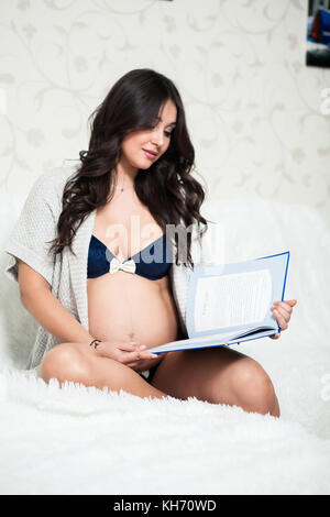 Cute happy pregnant woman sur canapé confortable avec réserve dans la chambre Banque D'Images