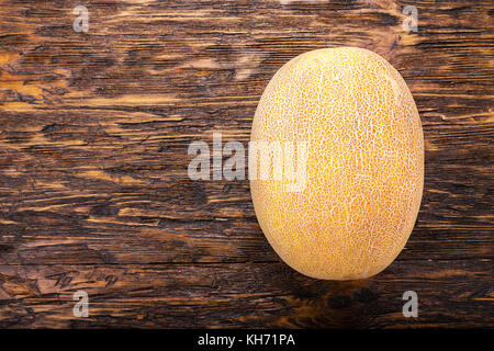 Tout un melon mûr sur une table marron foncé Banque D'Images