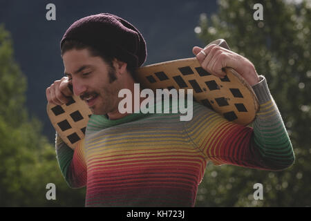 Thoughtful man holding skateboard dans skate park Banque D'Images